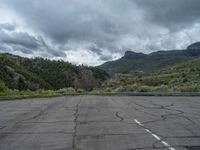 a mountain sits in the distance in a parking lot with a few trees and shrubbery