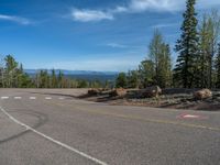 the mountains are visible in the distance from this wide, empty road, overlooking a wide landscape and forest