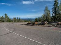 the mountains are visible in the distance from this wide, empty road, overlooking a wide landscape and forest