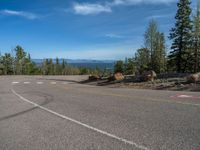 the mountains are visible in the distance from this wide, empty road, overlooking a wide landscape and forest