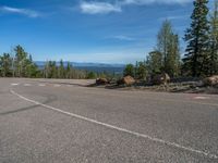 the mountains are visible in the distance from this wide, empty road, overlooking a wide landscape and forest