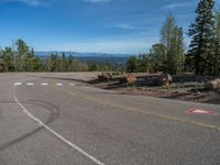 the mountains are visible in the distance from this wide, empty road, overlooking a wide landscape and forest