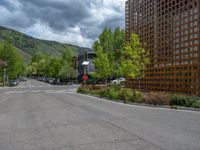 street corner with tree on the corner of the corner and a building behind it that is surrounded by multiple windows and a perforated brown lattice