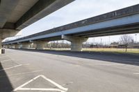 a view underneath an overpass from a parking area below a bridge as people ride on bicycles