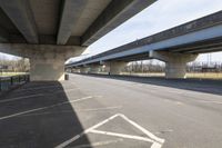 a view underneath an overpass from a parking area below a bridge as people ride on bicycles