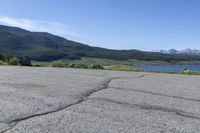 a fire hydrant sits in the street with a lake in the distance and mountains in the background