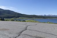 a fire hydrant sits in the street with a lake in the distance and mountains in the background