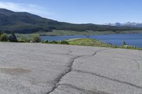 a fire hydrant sits in the street with a lake in the distance and mountains in the background