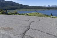 a fire hydrant sits in the street with a lake in the distance and mountains in the background