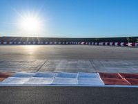 a photo of a dirt race track with sun setting in the distance of the track