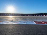 a photo of a dirt race track with sun setting in the distance of the track