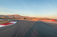 a photo of a dirt race track with sun setting in the distance of the track