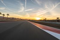 a photo of a dirt race track with sun setting in the distance of the track