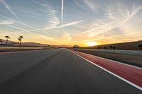 a photo of a dirt race track with sun setting in the distance of the track