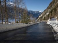 a paved road winds around the mountains next to a mountain road that has snow on it