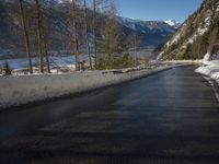 a paved road winds around the mountains next to a mountain road that has snow on it