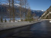 a paved road winds around the mountains next to a mountain road that has snow on it