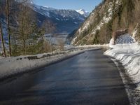 a paved road winds around the mountains next to a mountain road that has snow on it