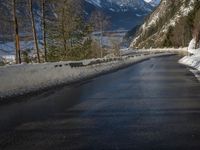 a paved road winds around the mountains next to a mountain road that has snow on it