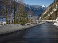 a paved road winds around the mountains next to a mountain road that has snow on it