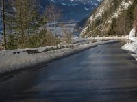 a paved road winds around the mountains next to a mountain road that has snow on it