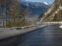 a paved road winds around the mountains next to a mountain road that has snow on it