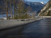 a paved road winds around the mountains next to a mountain road that has snow on it