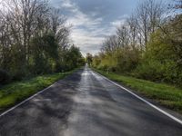 a long asphalt road that is not paved yet has grass on both sides of each side