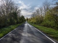 a long asphalt road that is not paved yet has grass on both sides of each side