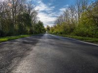 a long asphalt road that is not paved yet has grass on both sides of each side