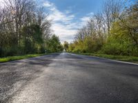 a long asphalt road that is not paved yet has grass on both sides of each side