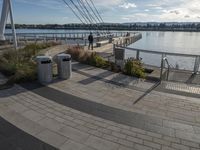 people walk along the river in the evening along the boardwalk in an urban area with concrete floors