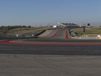 an empty track at a motorsports club with some red and white stripeing on it