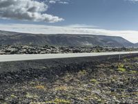 a motorcycle is sitting on the side of an asphalt road in a large rocky field