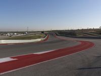 an empty track at a motorsports club with some red and white stripeing on it