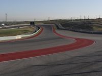 an empty track at a motorsports club with some red and white stripeing on it