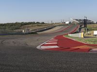 an empty track at a motorsports club with some red and white stripeing on it