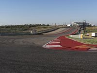 an empty track at a motorsports club with some red and white stripeing on it