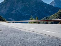 a road with a sign on the side of it next to a body of water with mountains in the background