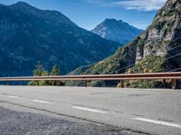 a road with a sign on the side of it next to a body of water with mountains in the background