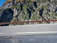 a wooden fence over the highway leading to a mountain side and a mountain behind it