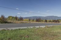 a view of the mountains with a street and grass near the side of it on a sunny day