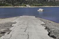 the road goes out onto the lake by itself on the shore with trees in the background