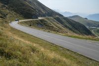 a motorcycle parked on a small mountain side road near mountains with no cars driving on it