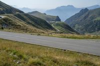 a motorcycle parked on a small mountain side road near mountains with no cars driving on it