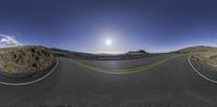 a photo with an oval shaped mirror over the road and mountains beyond it is bright blue sky with few white clouds