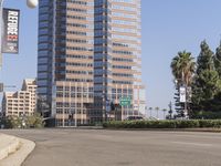 an empty road in front of tall buildings near a street with trees on one side and cars on the other