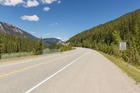 the highway is narrow and winding into a lake and mountains with trees in the distance