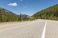 the highway is narrow and winding into a lake and mountains with trees in the distance