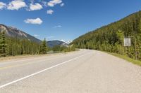 the highway is narrow and winding into a lake and mountains with trees in the distance